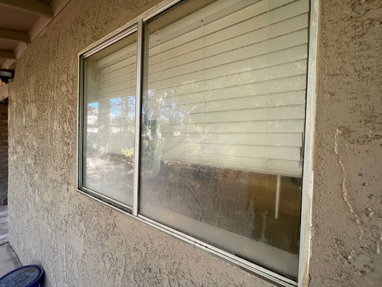 Las Vegas sliding window covered in heavy hard water mineral deposits and white calcium staining before professional removal