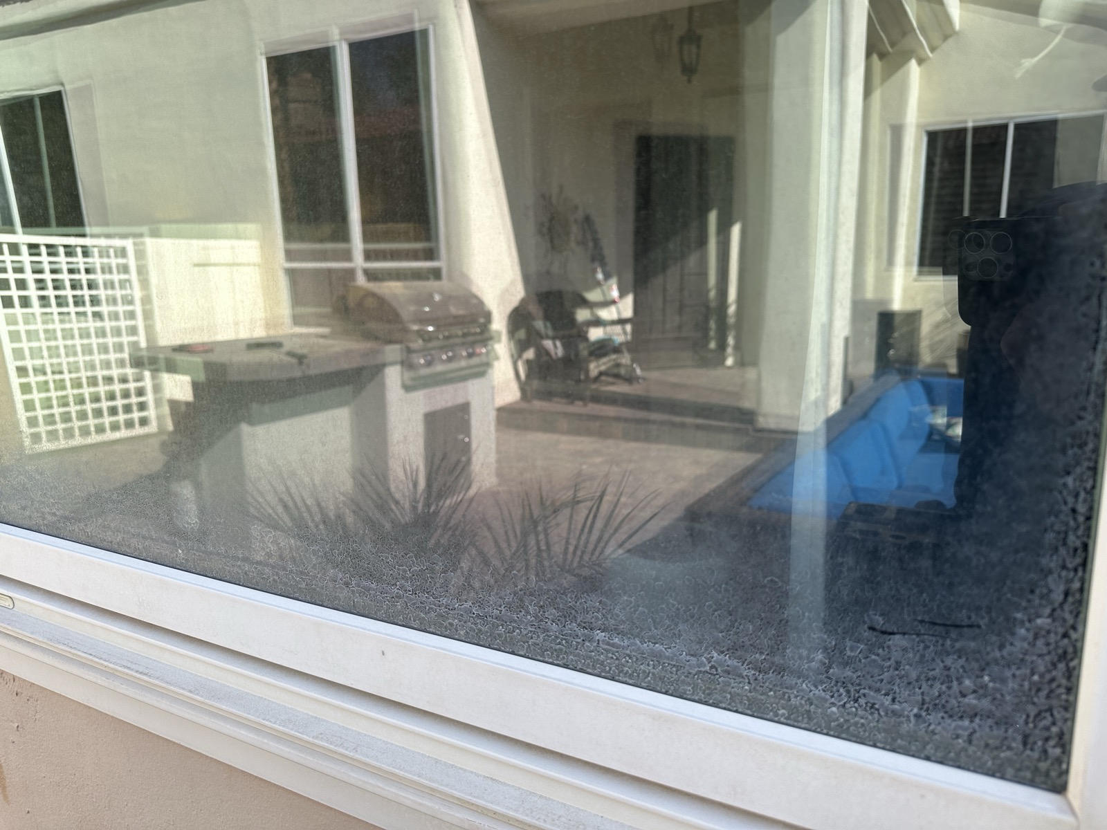 Window with hard water stains from sprinkler overspray