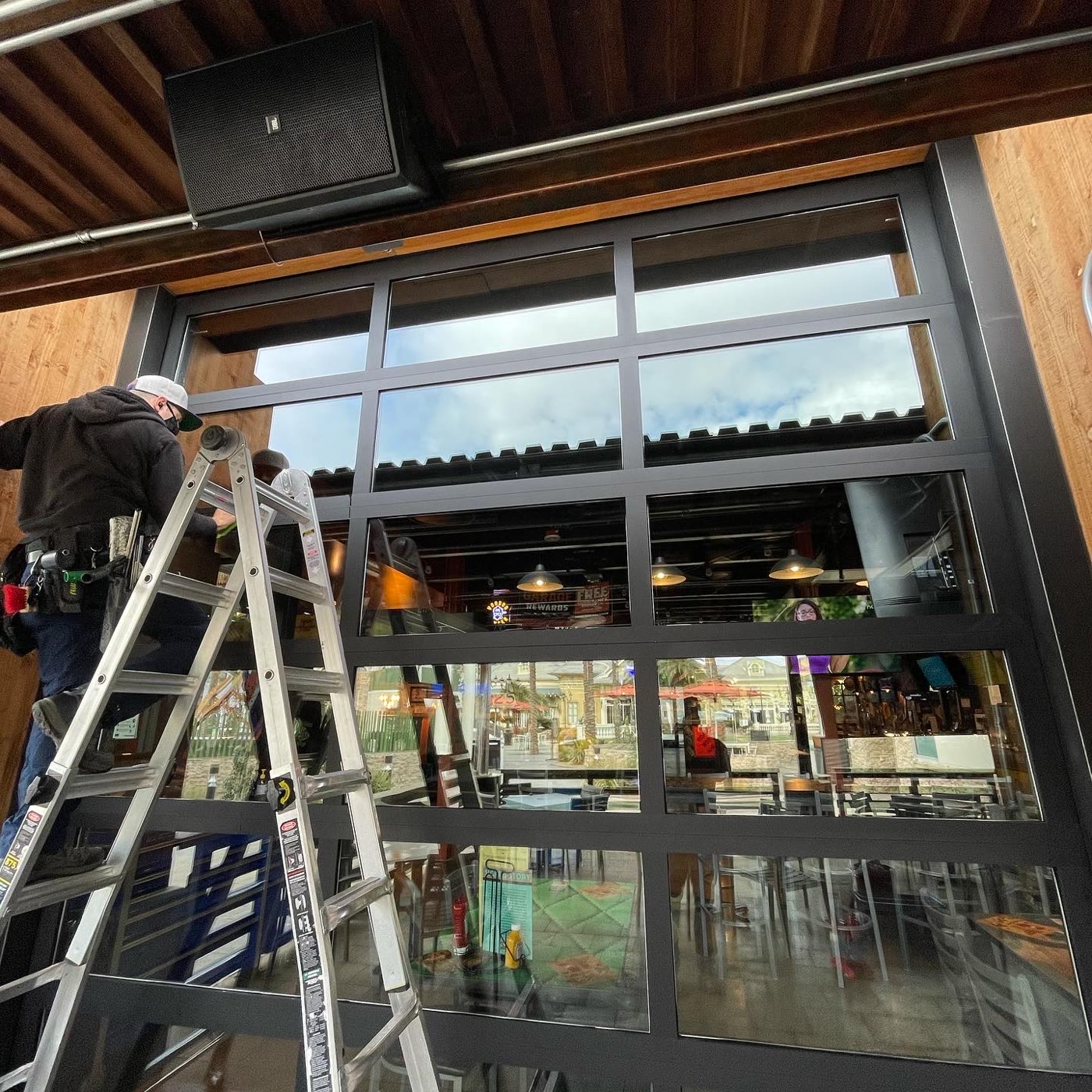Technician cleaning Sickies Garage Las Vegas restaurant windows from a ladder